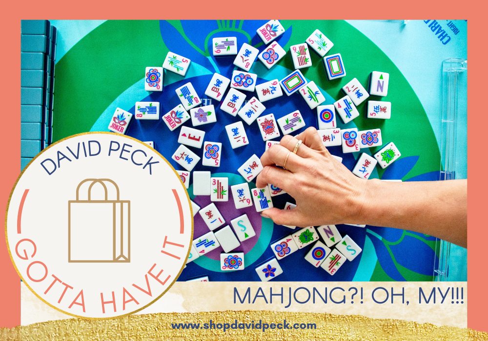 Hand of a mahjong player arranging mahjong tiles on a blue and green mahjong mat by Oh My Mahjong.