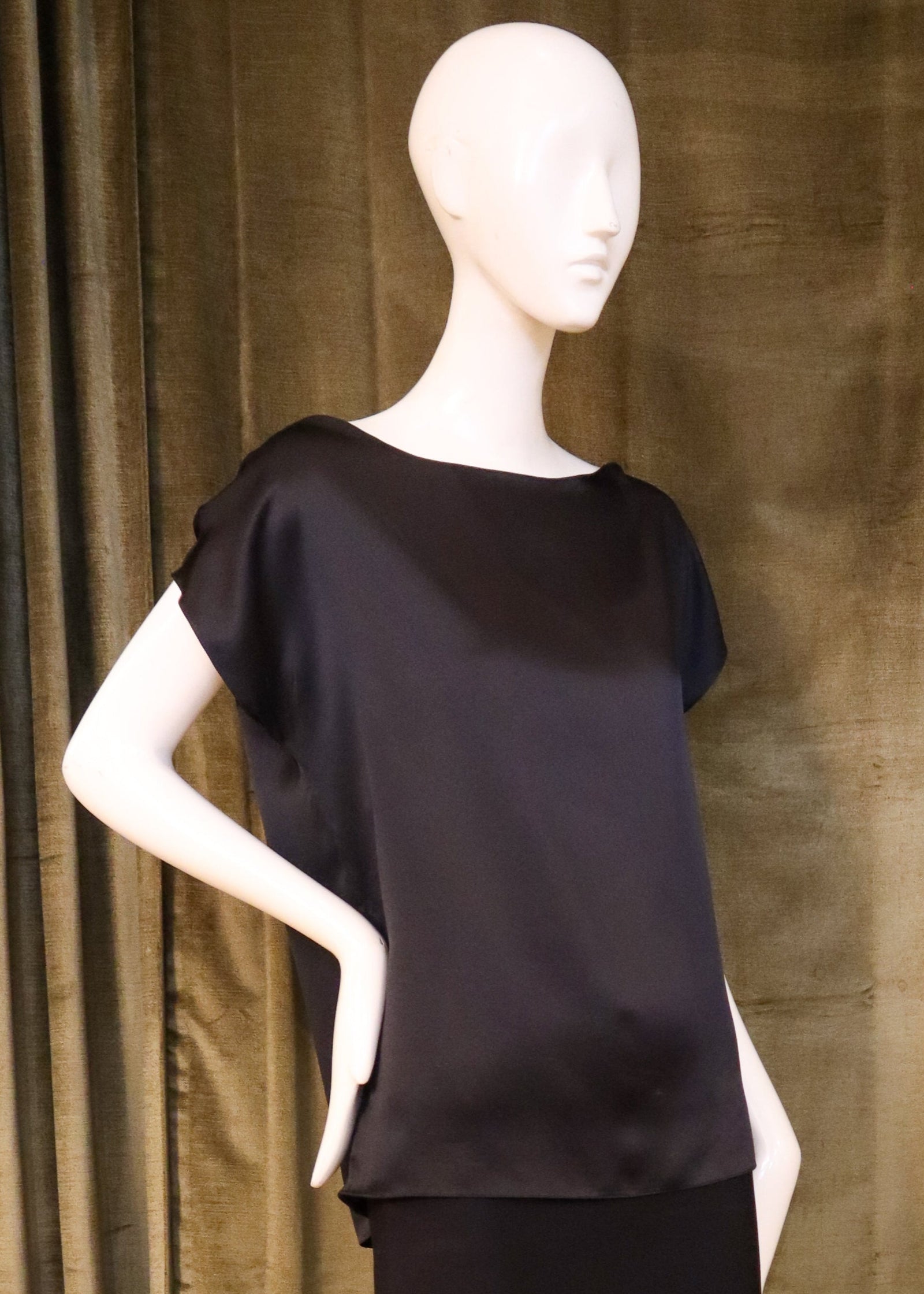 Mannequin wearing a black outfit against a brown curtain background with designed by David Peck.