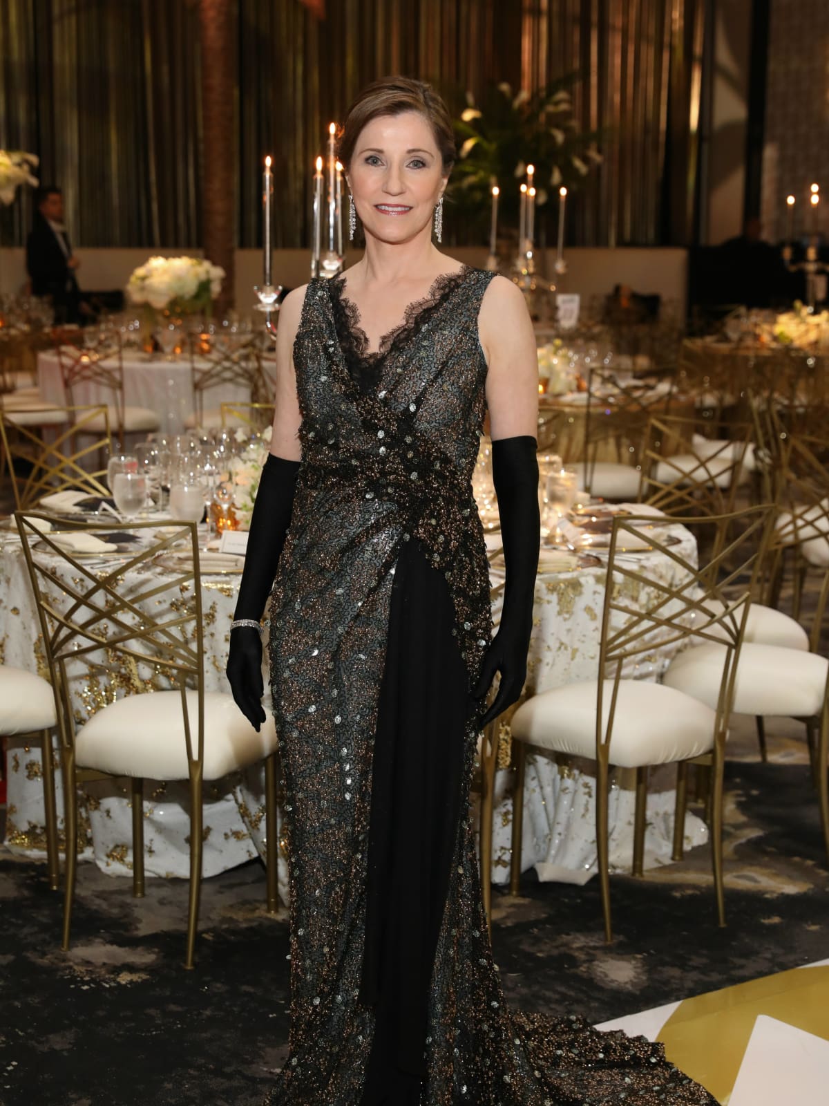 Dr. Liz Grimm, HGO opera chair, in a custom designed black, V-neck, and sequin embroidered gown with black gloves by David Peck at the Houston Opera Ball.