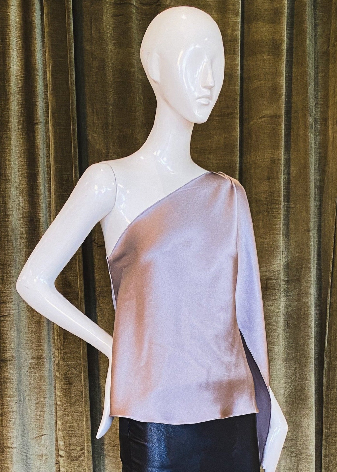 A mannequin displaying a pink one-shoulder top with scarf sleeve made of silk crepe back satin. Designed by David Peck.