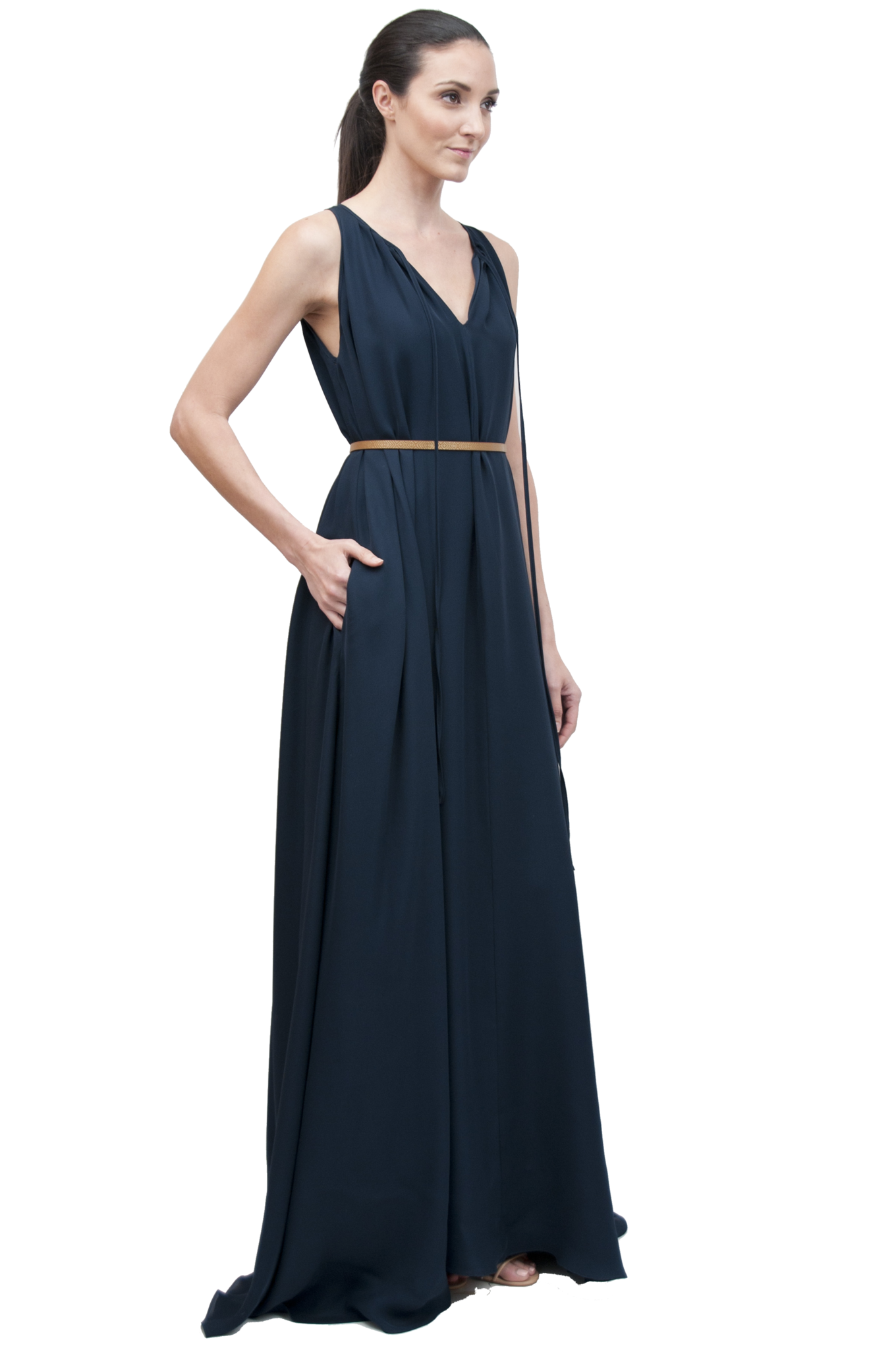 A woman wearing a navy blue, sleeveless, maxi-length gown with a tie neck and pockets, made of silk double georgette fabric. Designed by David Peck