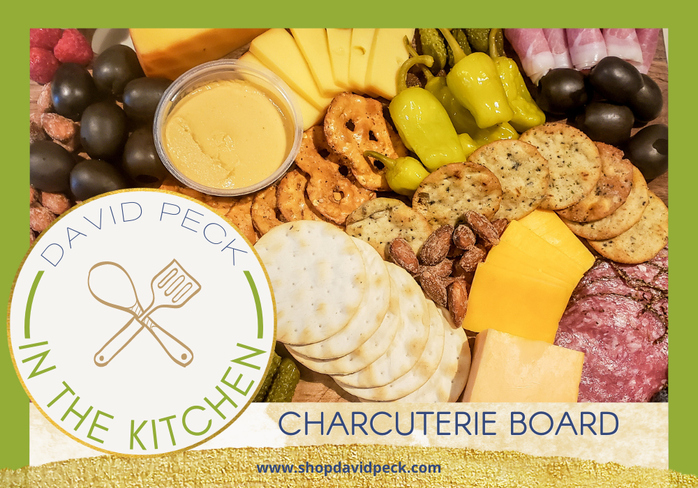 In the kitchen. pretzels, cheeses, crackers, pickles, salami, olives, nuts, peppers, prosciutto, and fruit on a wooden charcuterie board