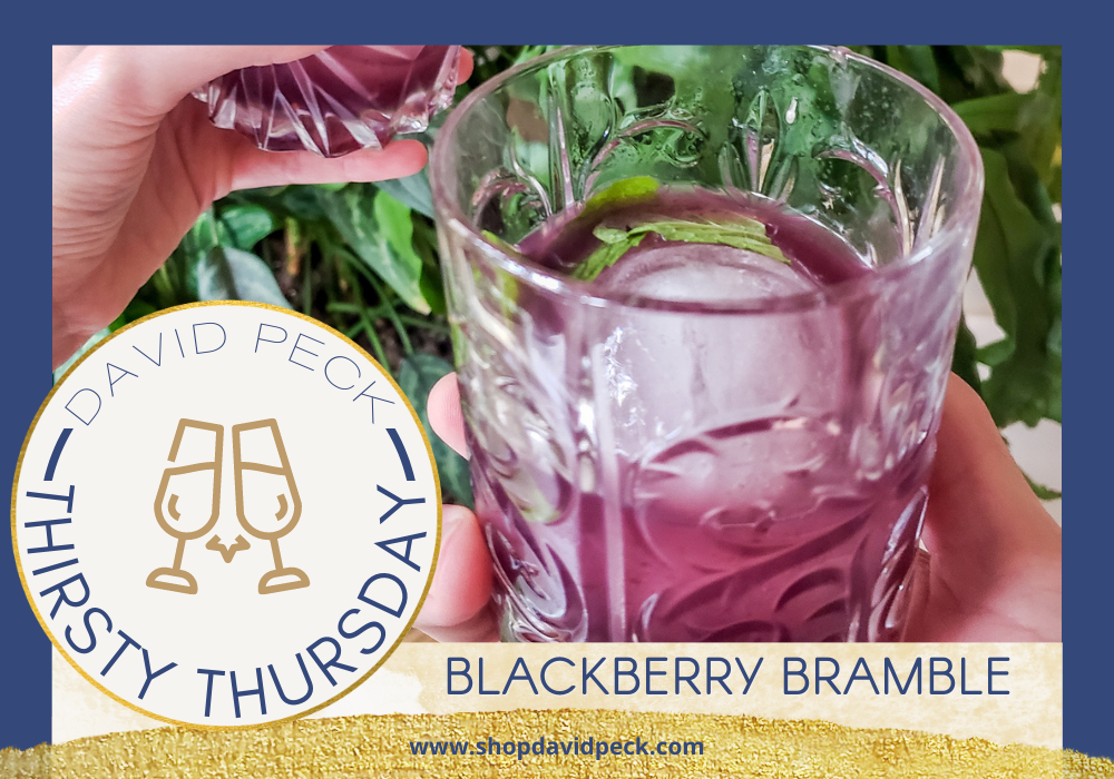 Thirsty Thursday. Hand holding crystal tumbler with blackberry bramble cocktail.