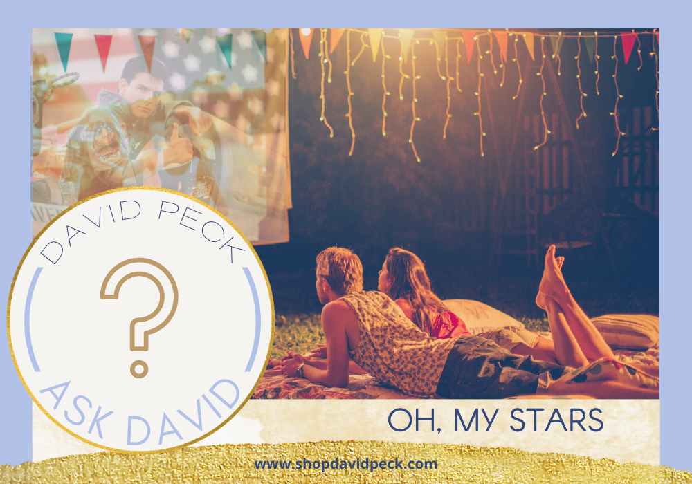 Ask David. Guy and Girl laying on their stomach outside watching a movie on a outdoor movie screen 
