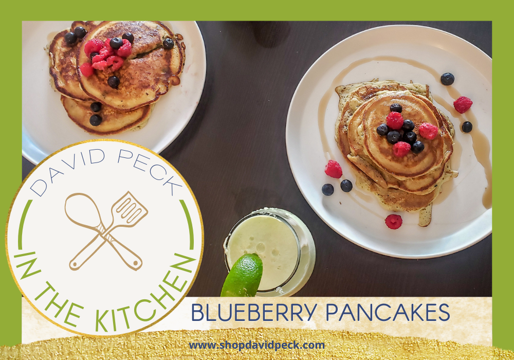 In the Kitchen. Blueberry pancakes on white plate topped with blueberries and raspberries drizzled with syrup.