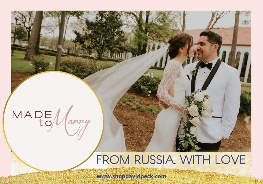 Made to Marry. Brunette bride and groom smiling and looking at each other in courtyard. Bride holding flower bouquet while vail blows in the wind.  