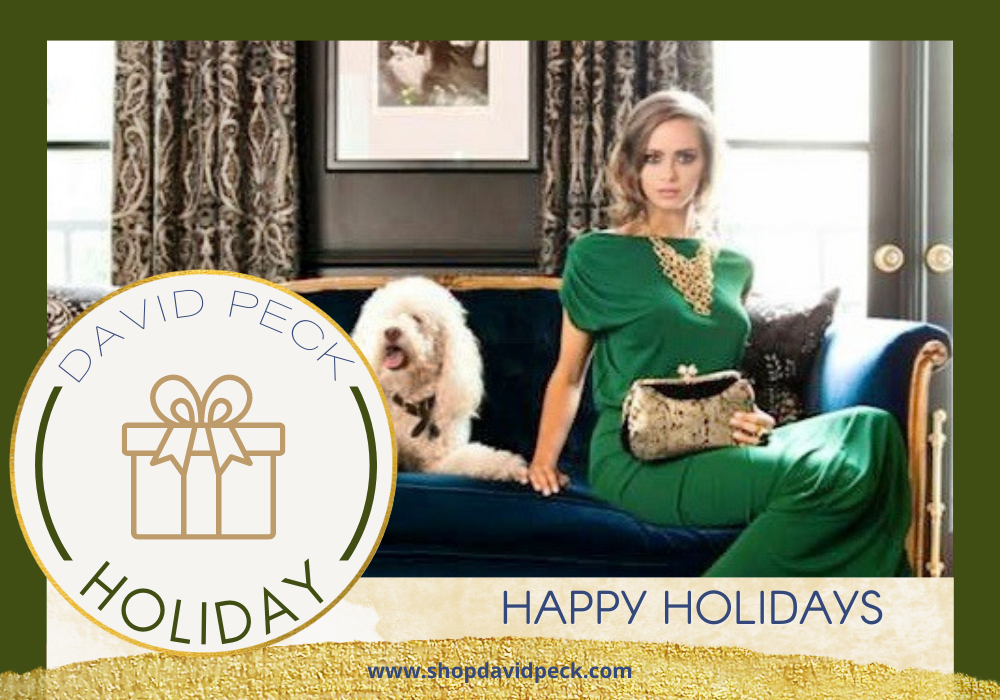 holiday. model in green david peck gown sitting on a dark couch next to a white dog in a luxury apartment