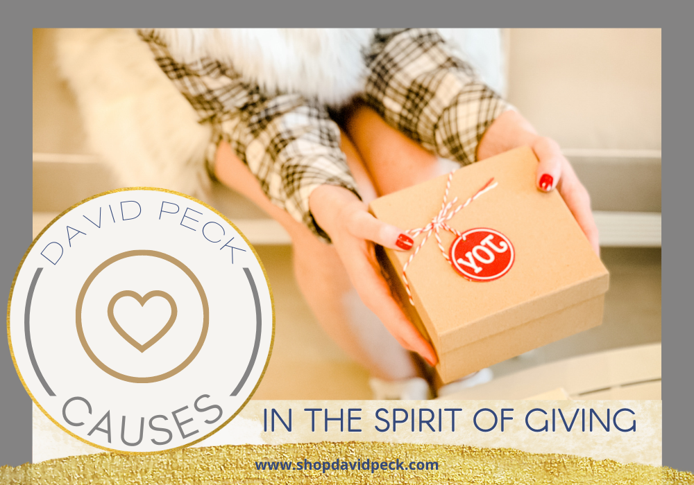 causes. woman with red nails wearing a plaid long sleeve dress and faux fur coat holding a brown gift box with tag that says joy