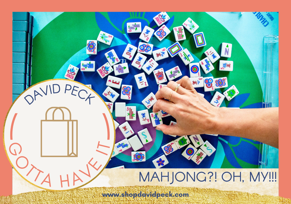 Hand of a mahjong player arranging mahjong tiles on a blue and green mahjong mat by Oh My Mahjong. 