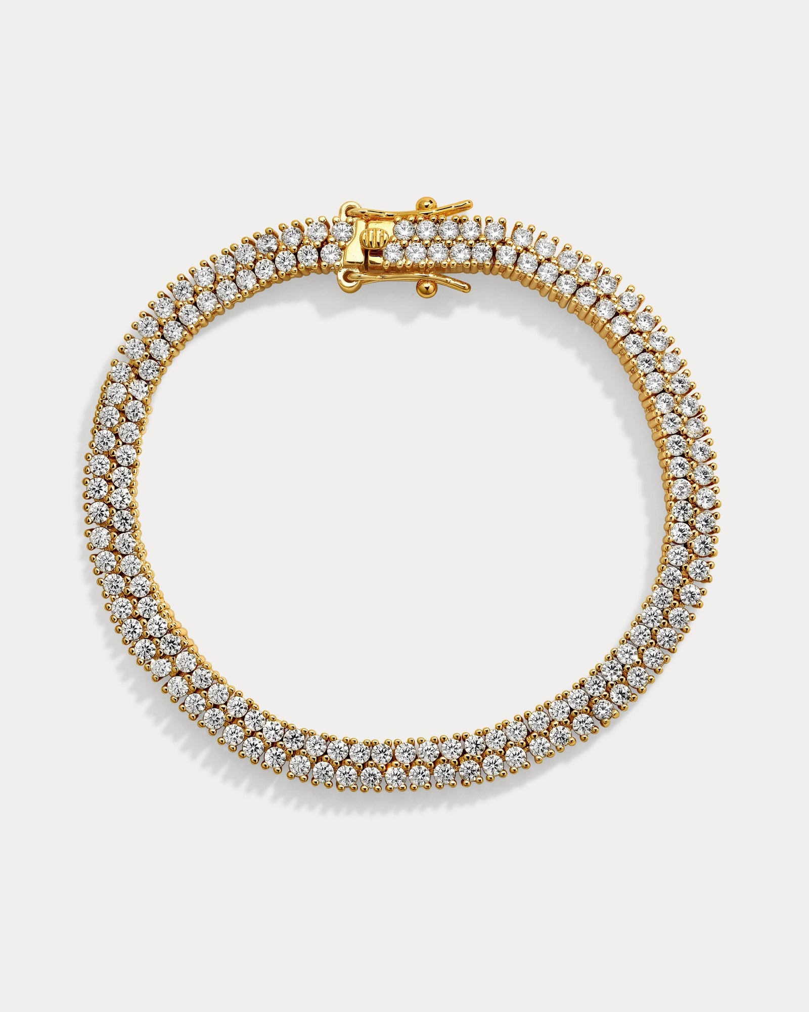 Gold bracelet with clear stones on a light gray background