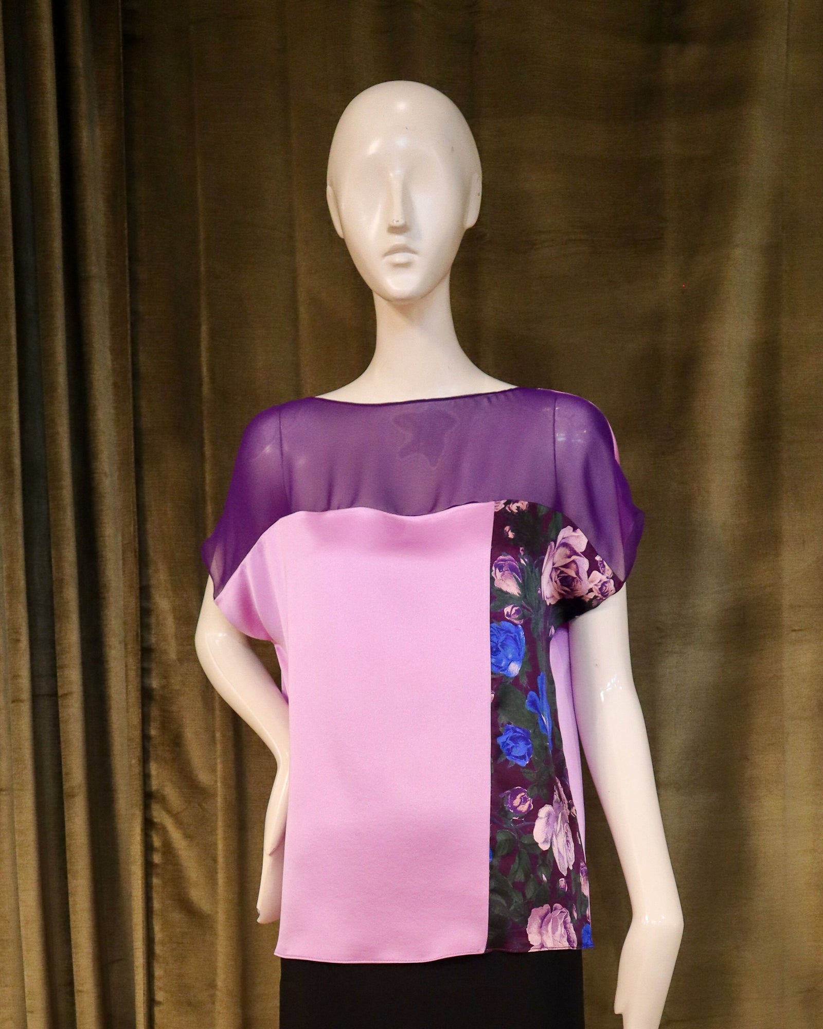 Mannequin wearing a floral top and black skirt against a olive curtain background. Designed by David Peck