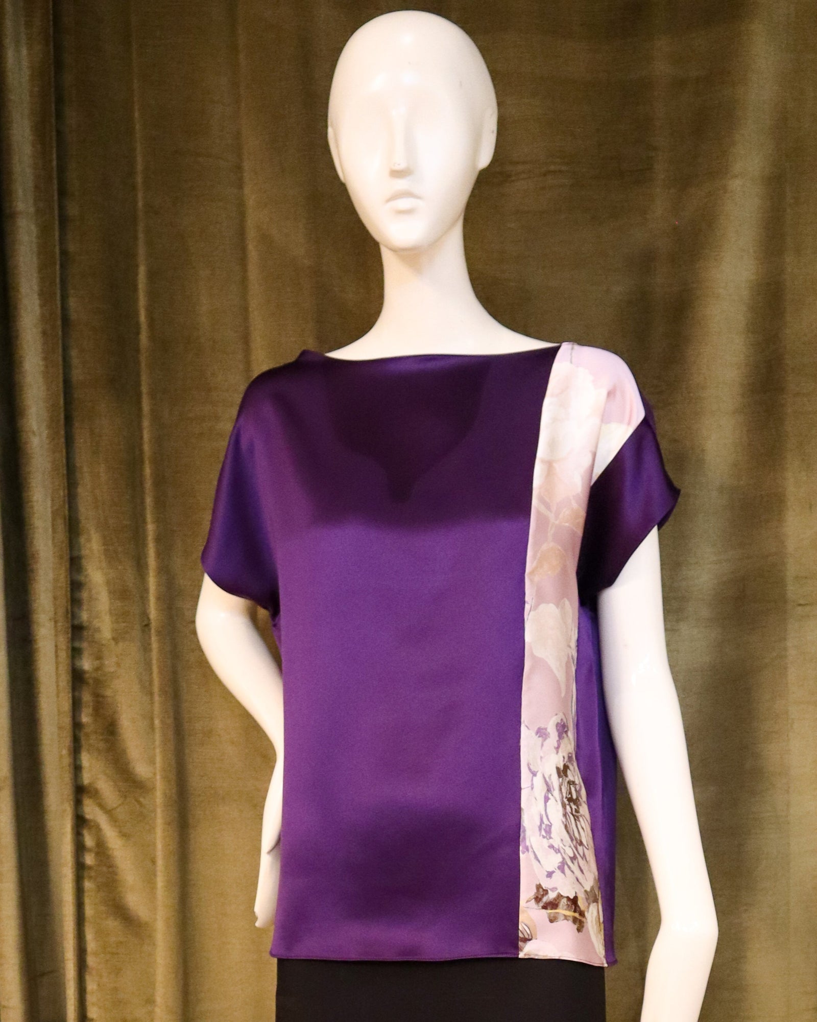 Mannequin wearing a floral top and black skirt against a green curtain. Designed by David Peck