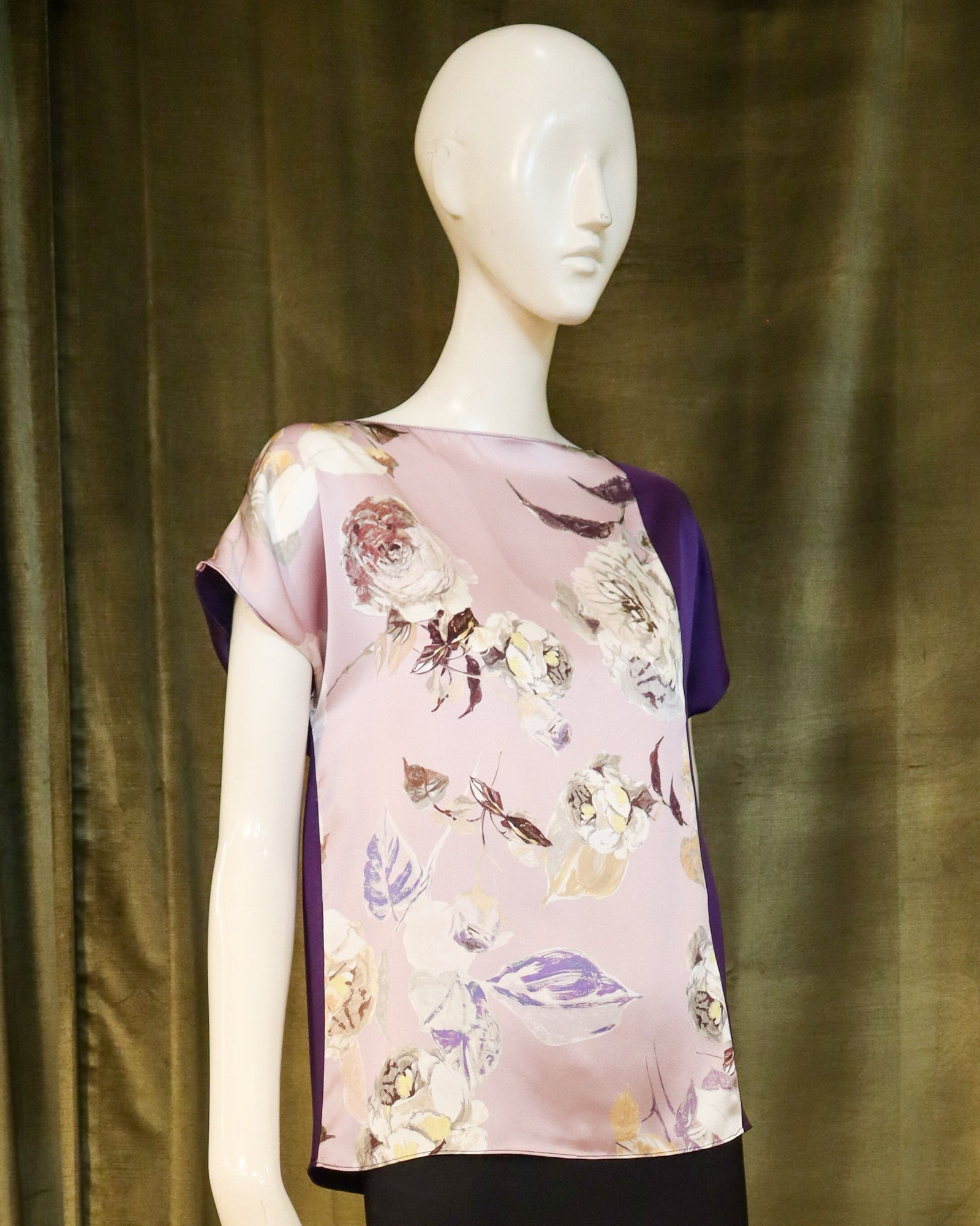 Mannequin wearing a floral top and black skirt against a green curtain. Designed by David Peck