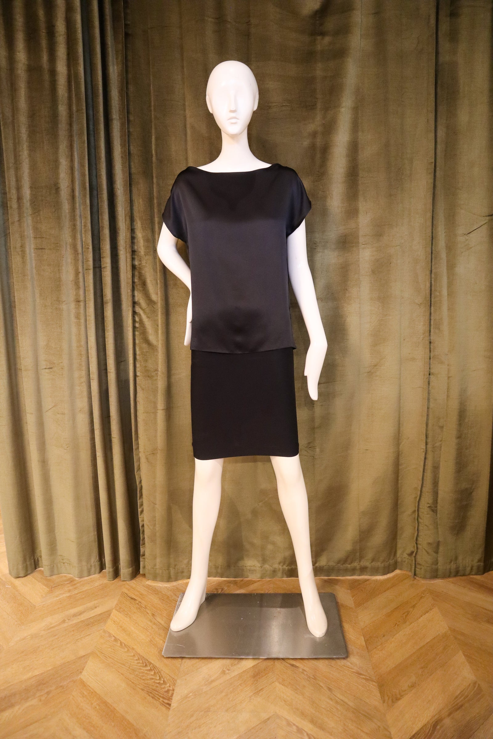 Mannequin wearing a black outfit against a brown curtain background with designed by David Peck.