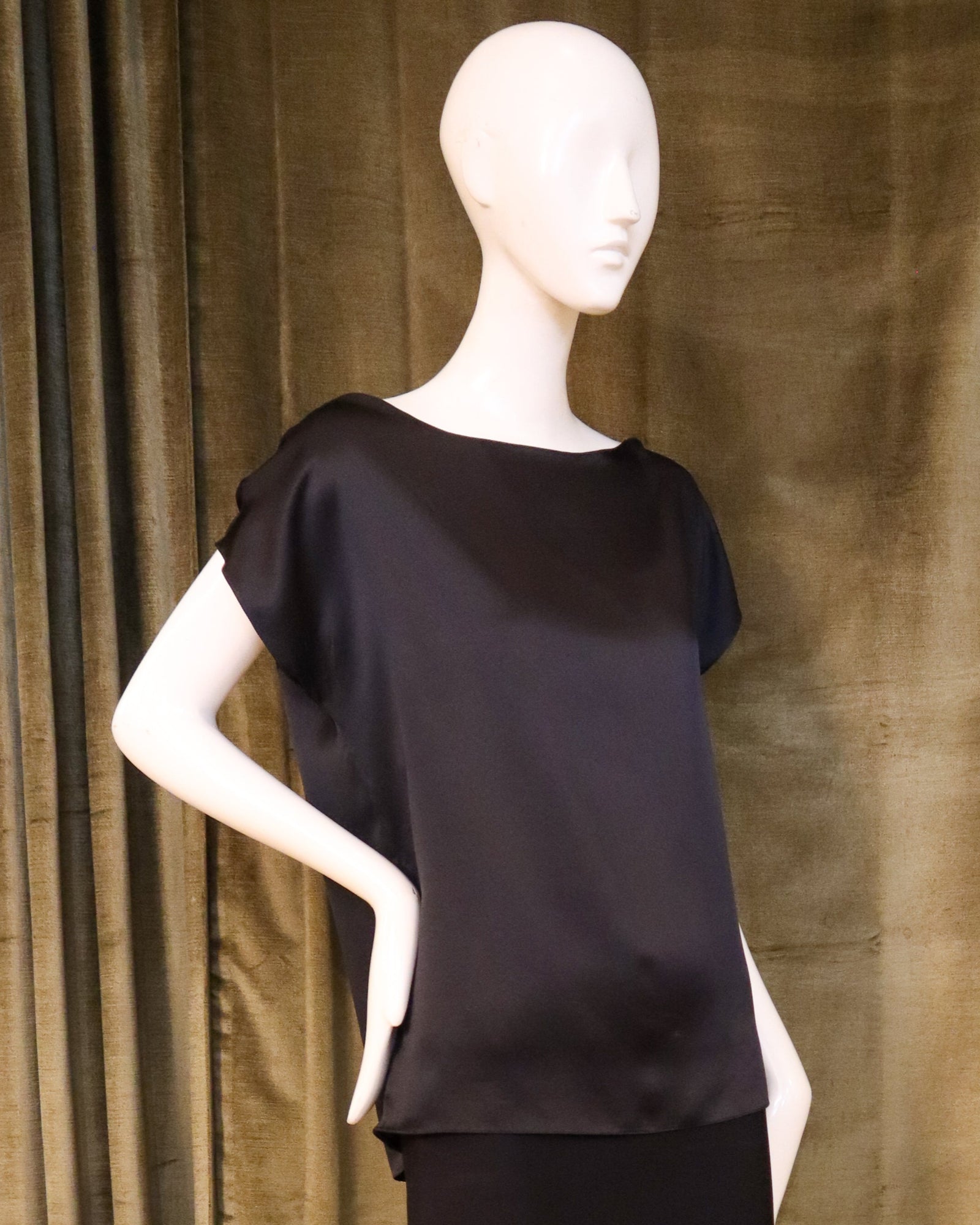 Mannequin wearing a black outfit against a brown curtain background with designed by David Peck.