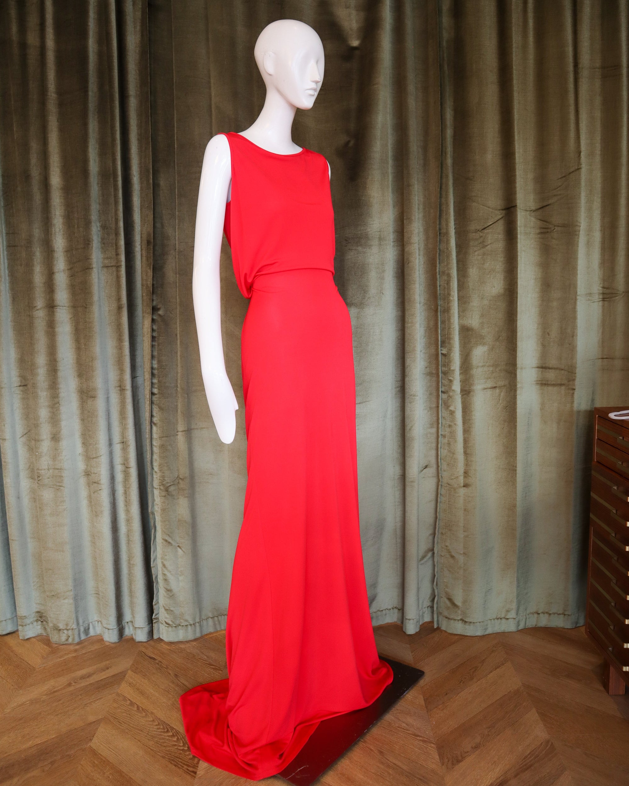 Red evening gown on a mannequin against a textured curtain background