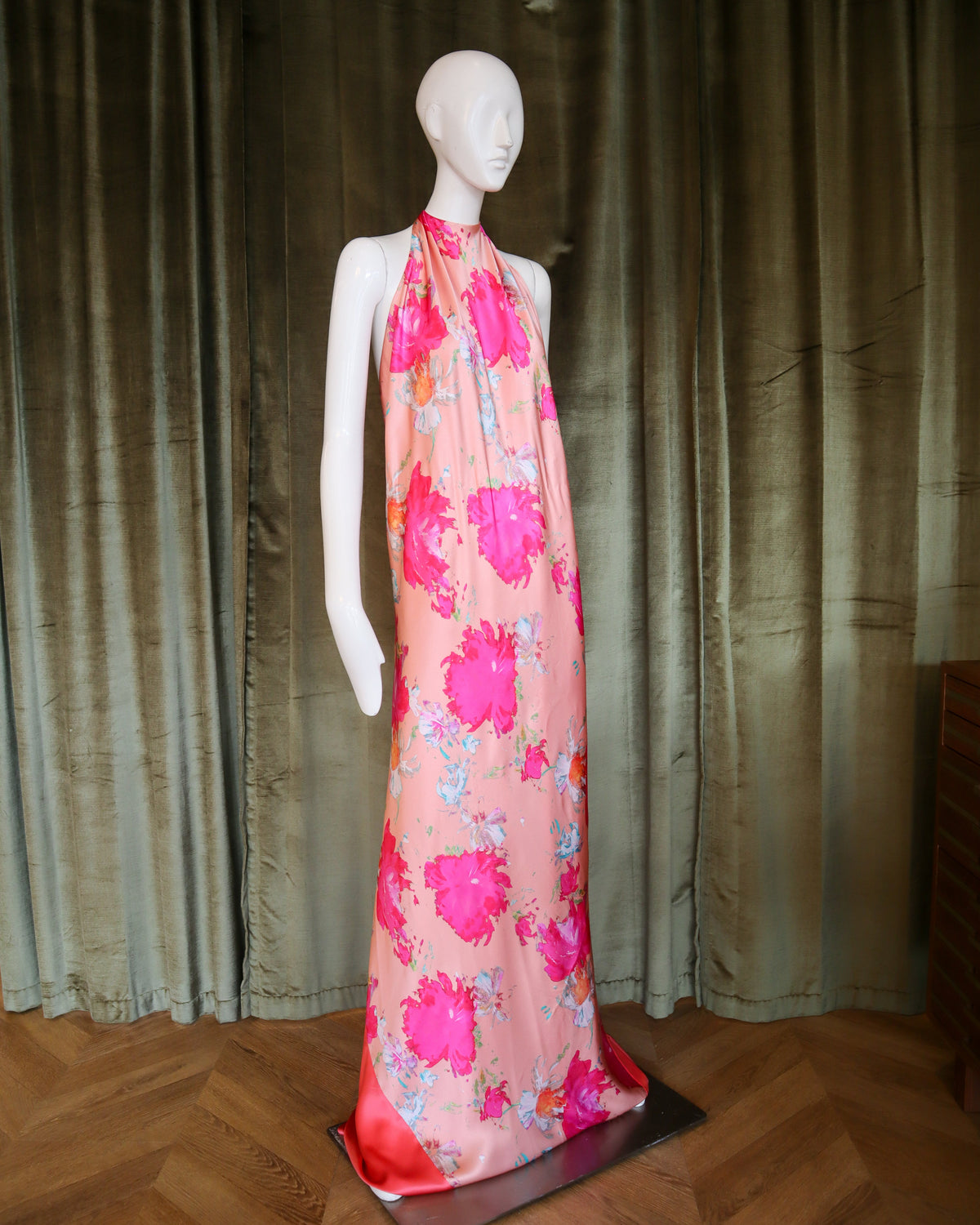 Mannequin wearing a pink floral dress against a curtain backdrop