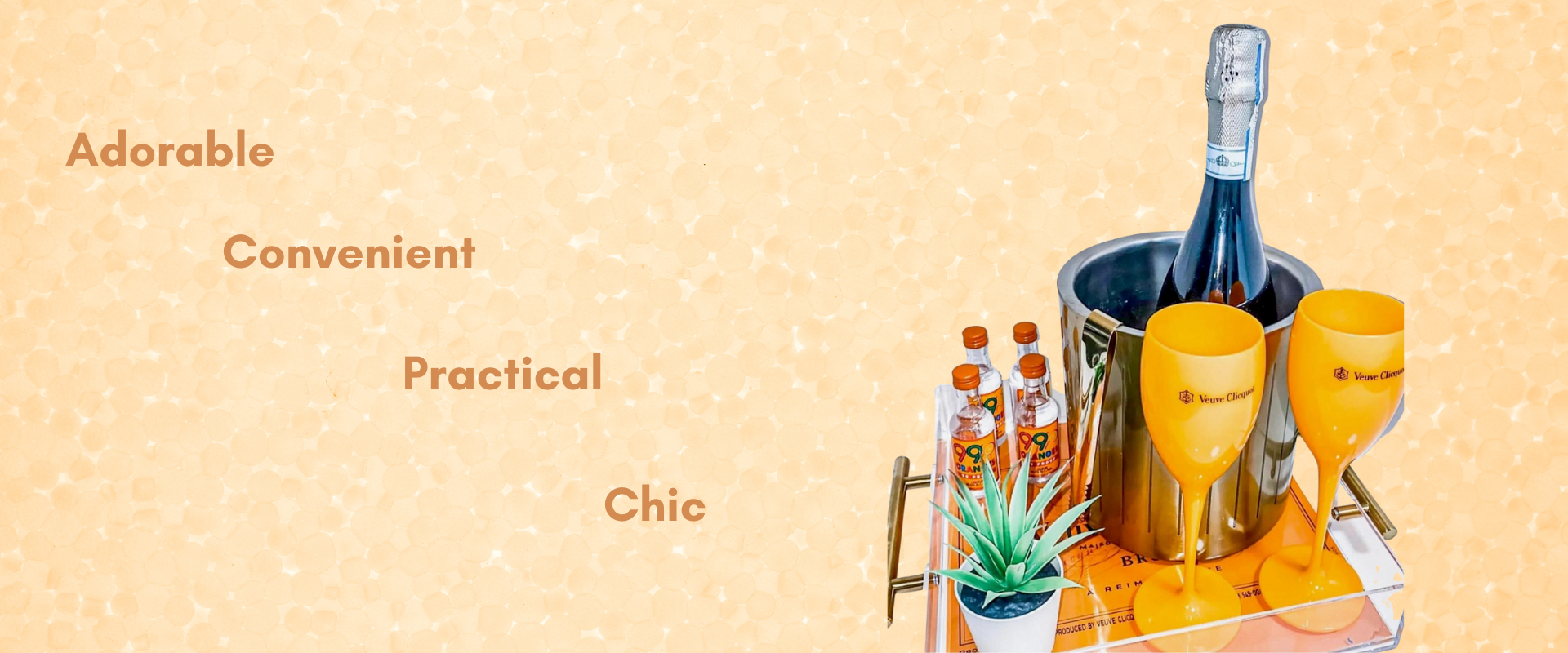 Adorable, Convenient, Practical, Chic. Two orange plastic champagne cups on top of an orange tray next to a plant, wine cooler, wine, and bottles.