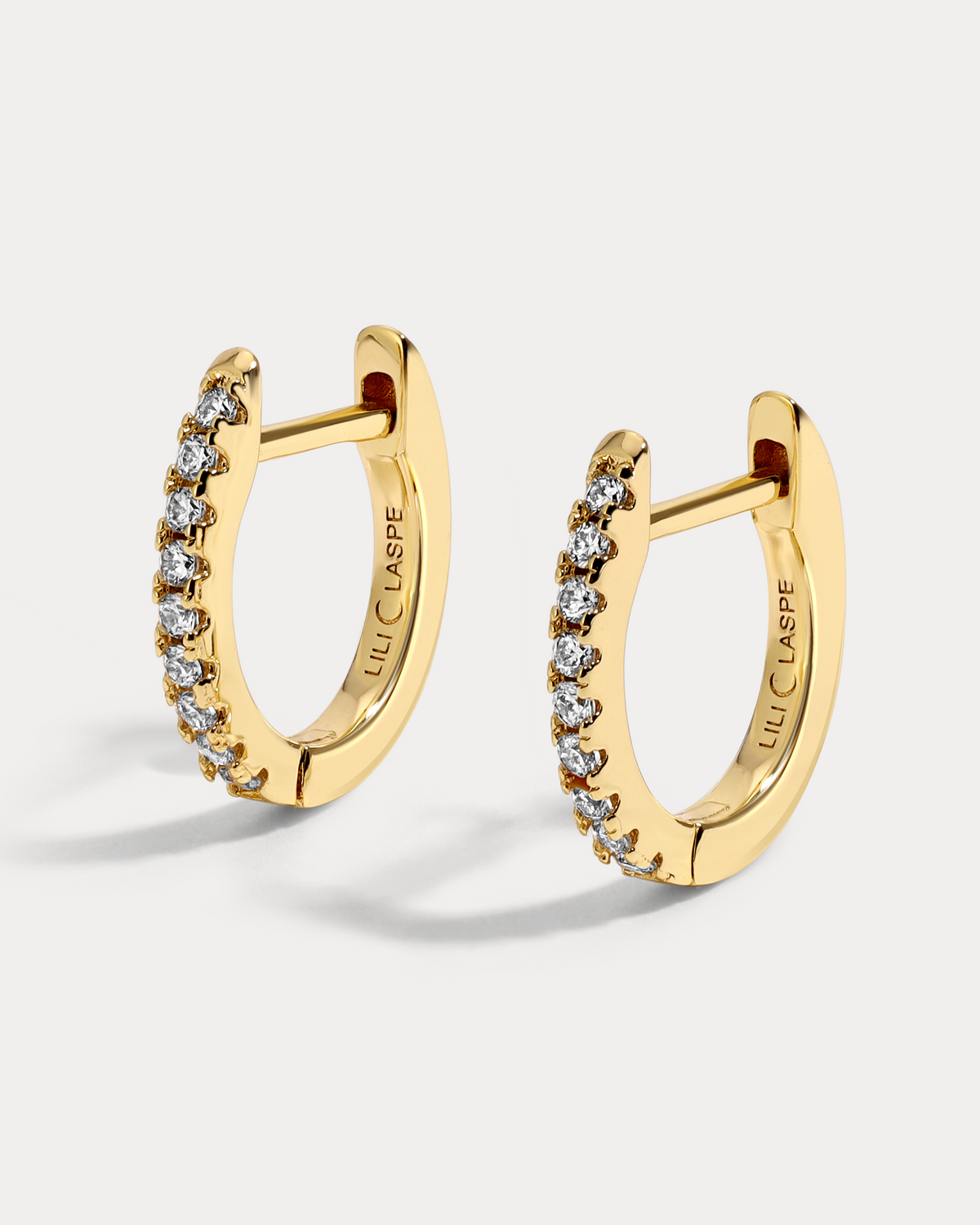Gold hoop earrings with embedded stones on a light gray background