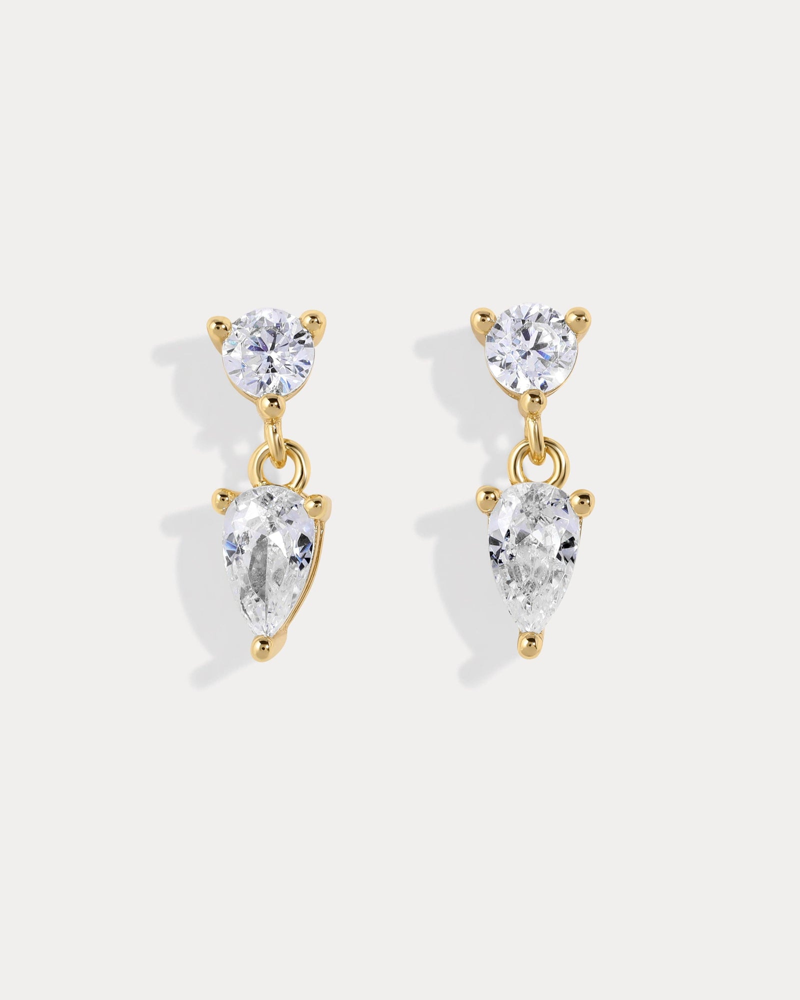 Pair of gold and clear teardrop earrings on a white background