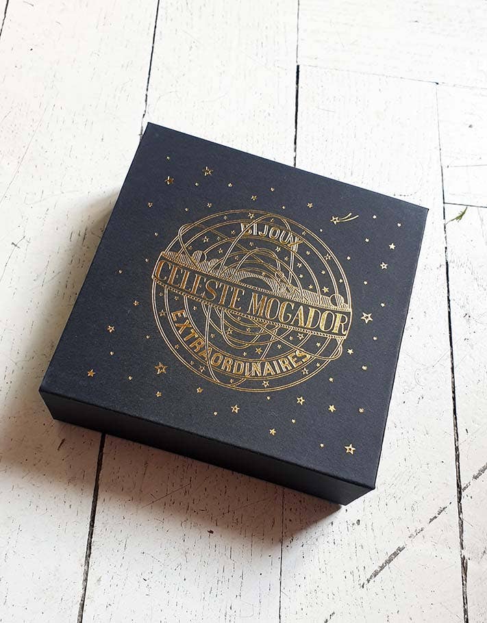 Black box with gold embossed text on a white wooden surface