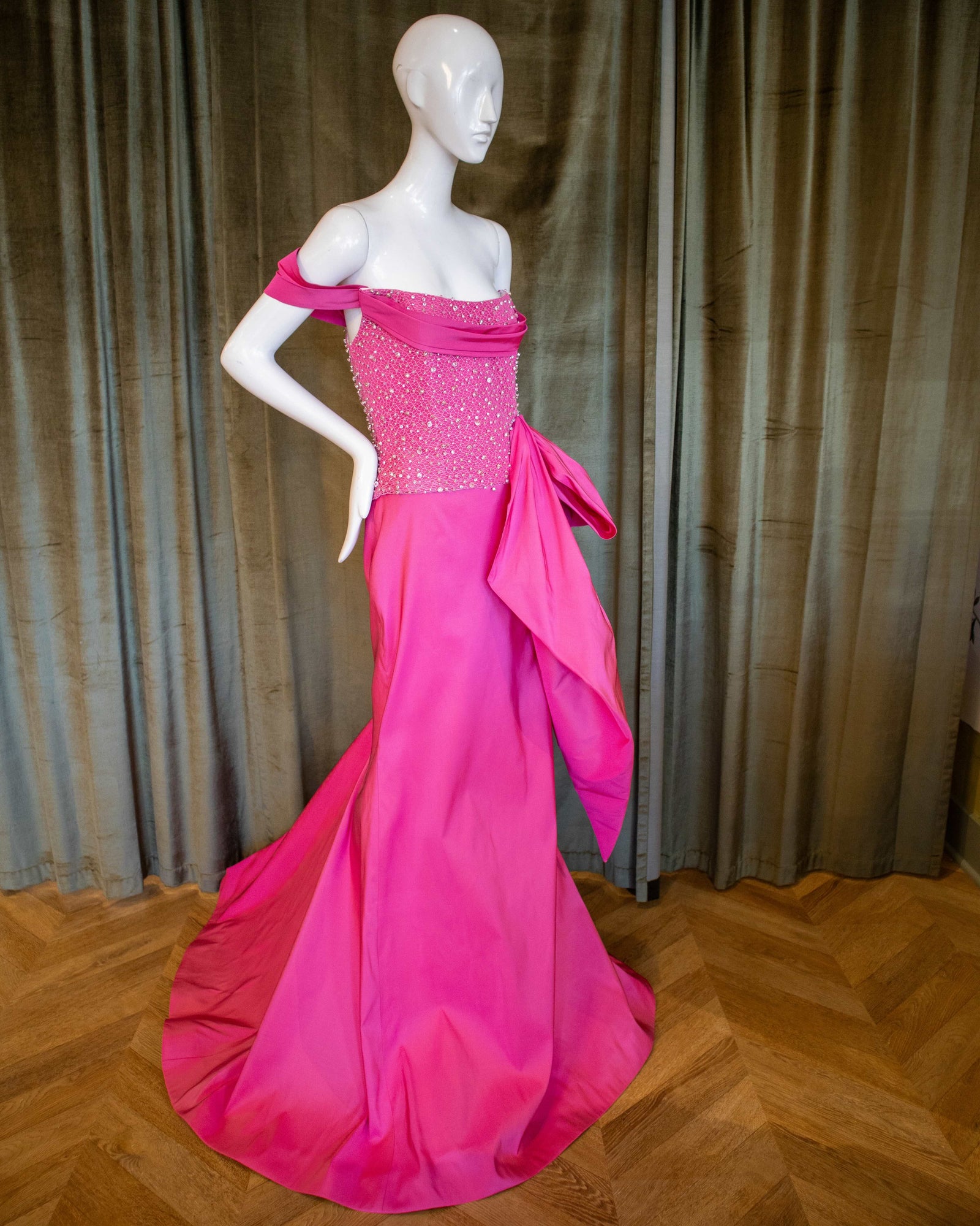 The image features a striking Barbie Bustier Top displayed on a mannequin. The top is crafted from a lustrous magenta silk faille and is detailed with an elegant crystal beading that adds a touch of glamour. Designed by David Peck