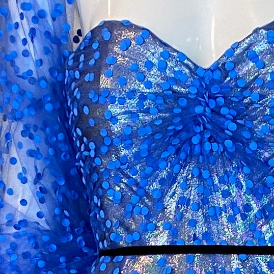 Blue beaded evening gown on a mannequin in a room with floral wallpaper.