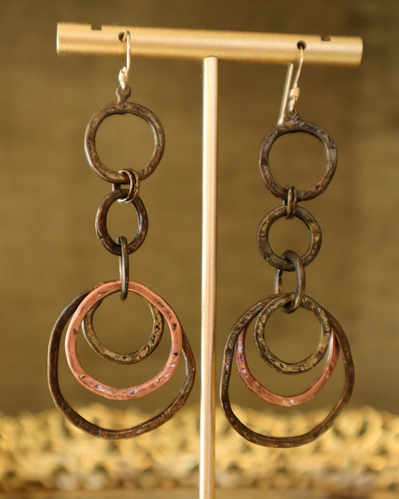 Pair of earrings with interconnected rings on a gold stand against a blurred background