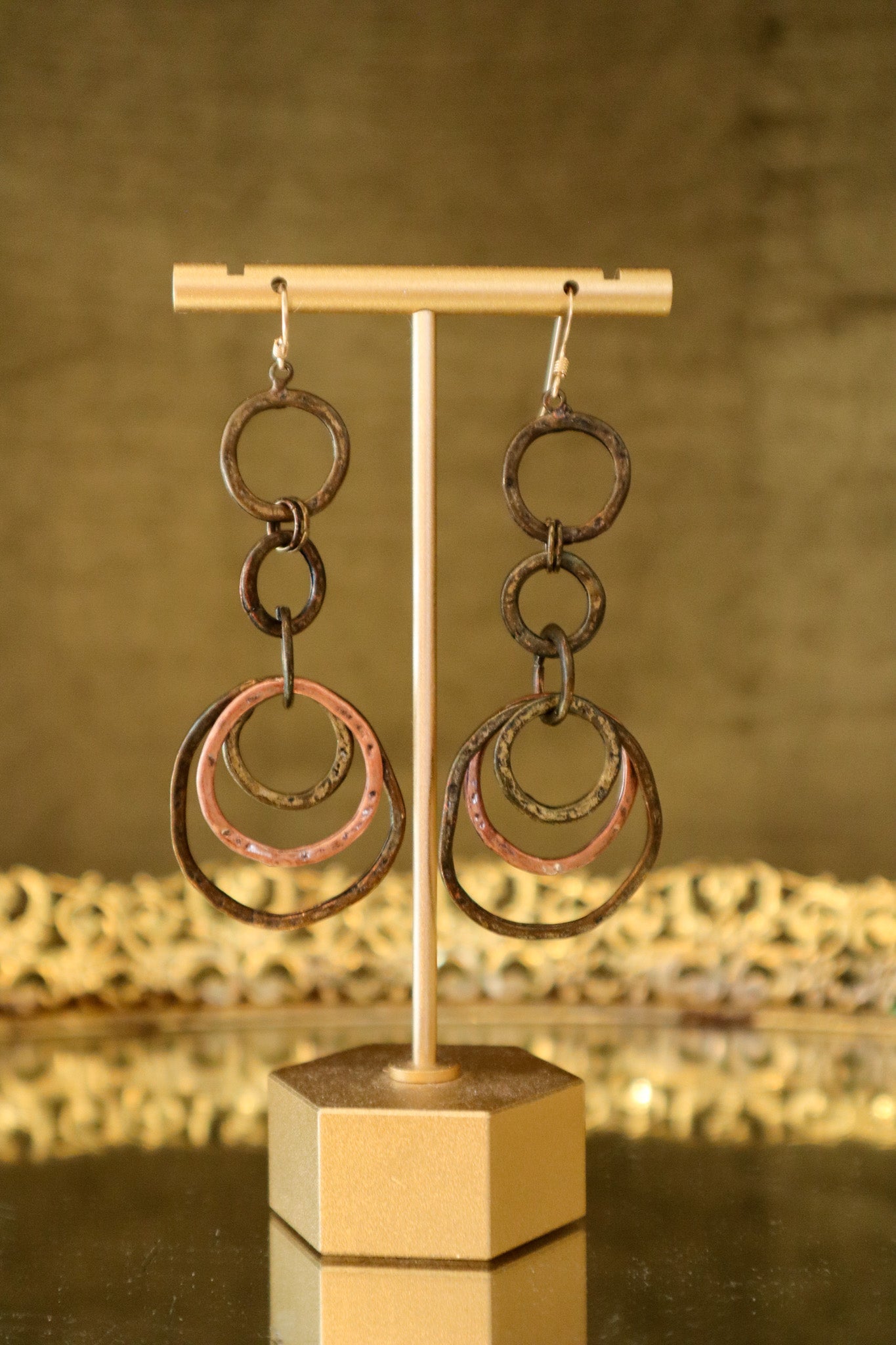 Pair of earrings with interconnected rings on a gold stand against a blurred background
