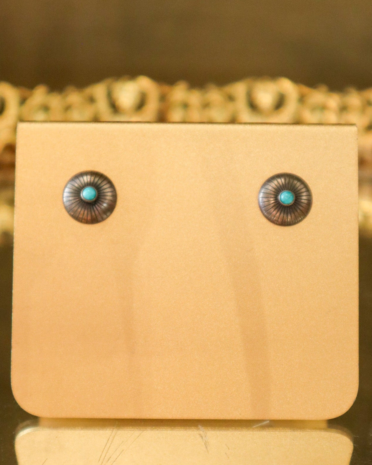 Pair of earrings with turquoise stones on a beige card against a blurred background