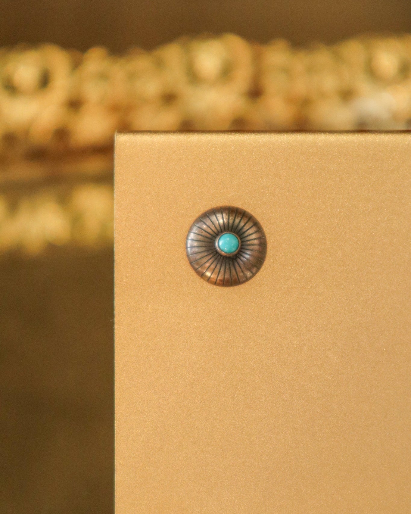 Pair of earrings with turquoise stones on a beige card against a blurred background