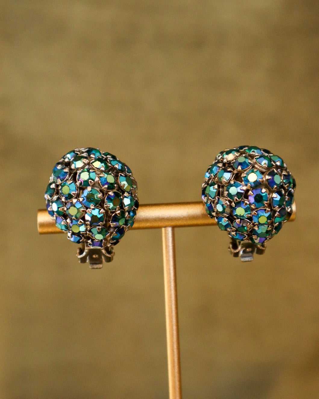 Pair of sparkling earrings on a stand with a blurred background