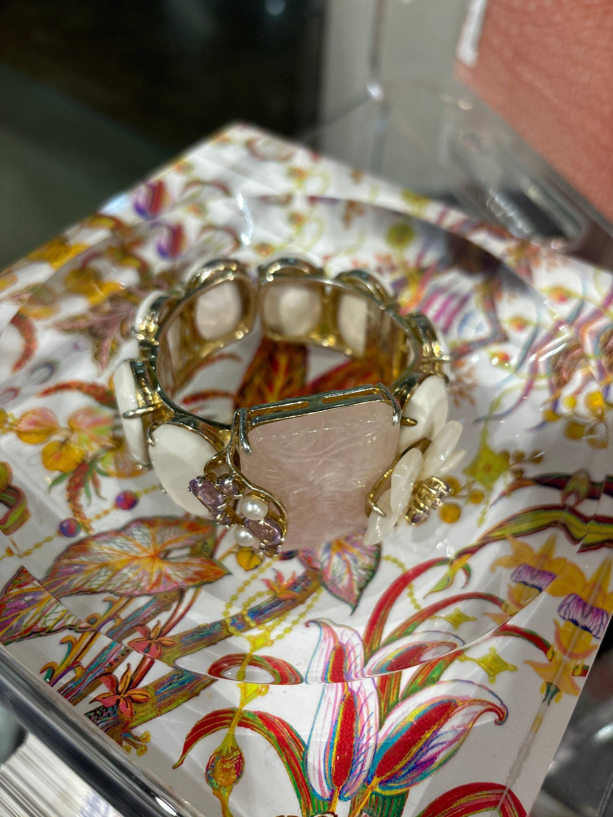 Decorative jewelry box with a colorful floral design on a reflective surface.